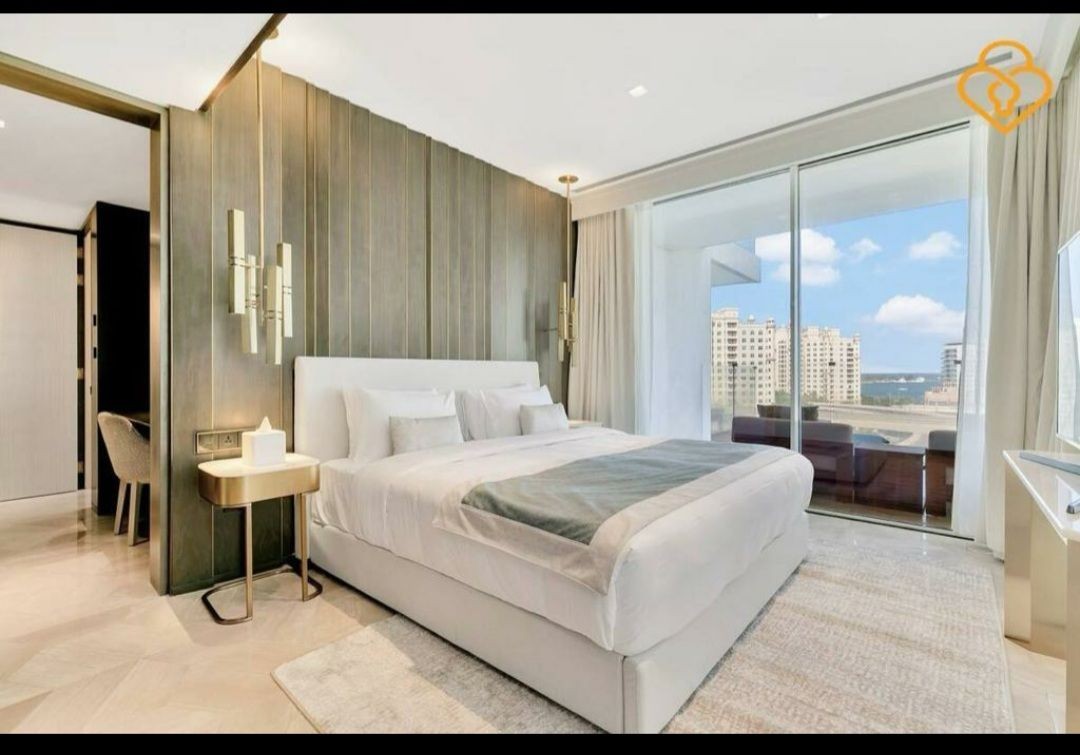 Luxurious bedroom with modern decor, large bed, and balcony view of cityscape.